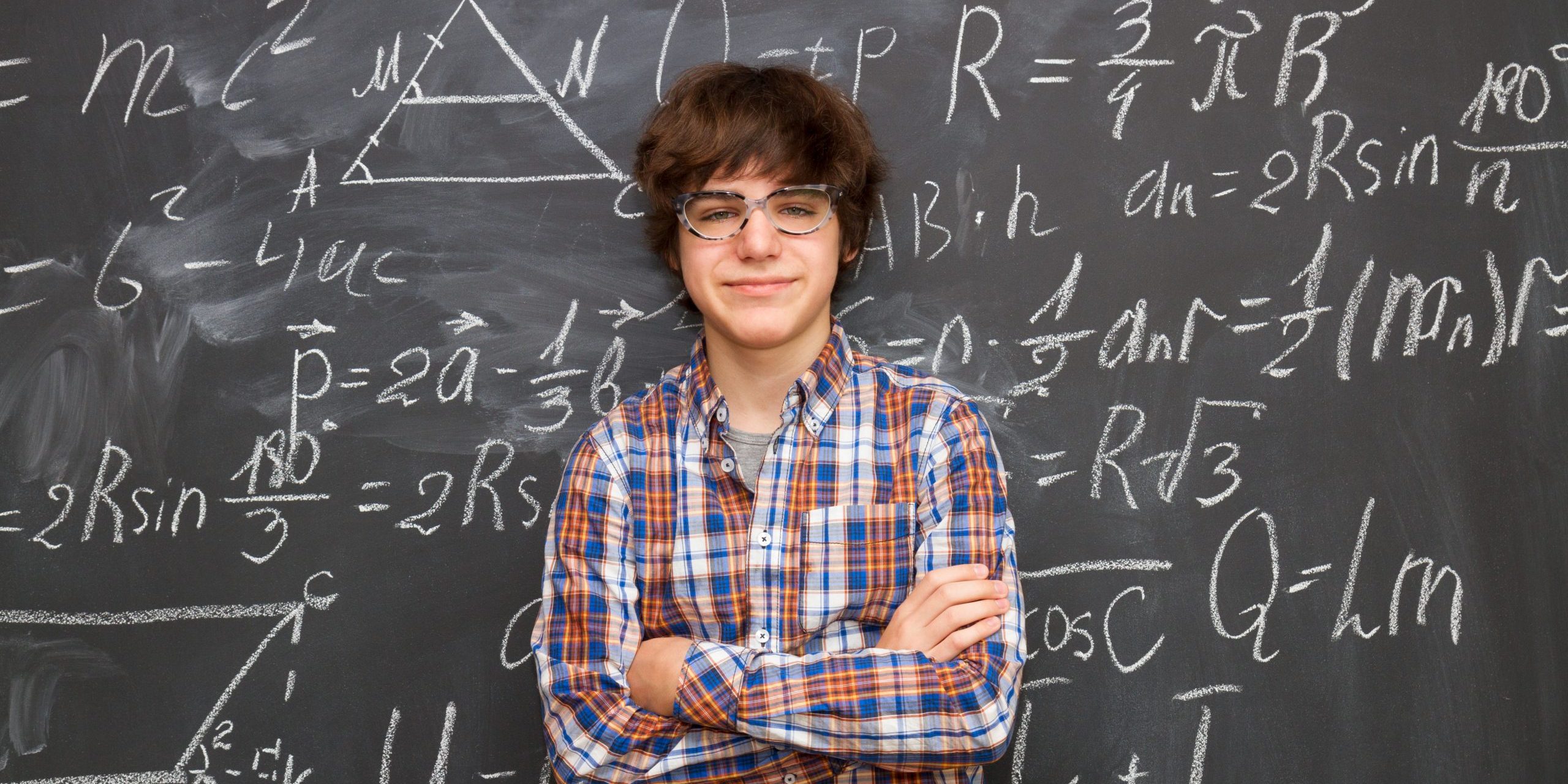 Teen,Boy,In,Glasses,,Blackboard,Filled,With,Math,Formulas,Background