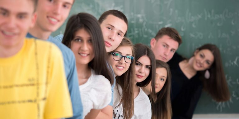 Group,Of,Teenagers,Posing,In,Classroom,Standing,In,A,Row
